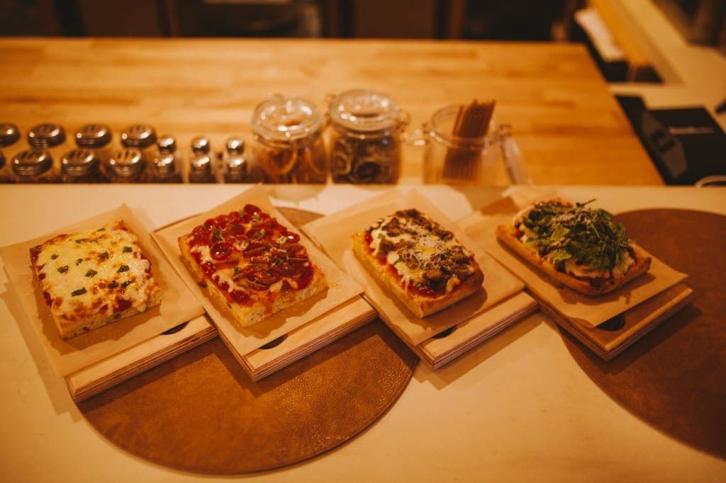 Four square pizza slices lined up on the bar at The Analogue Room in Solvang