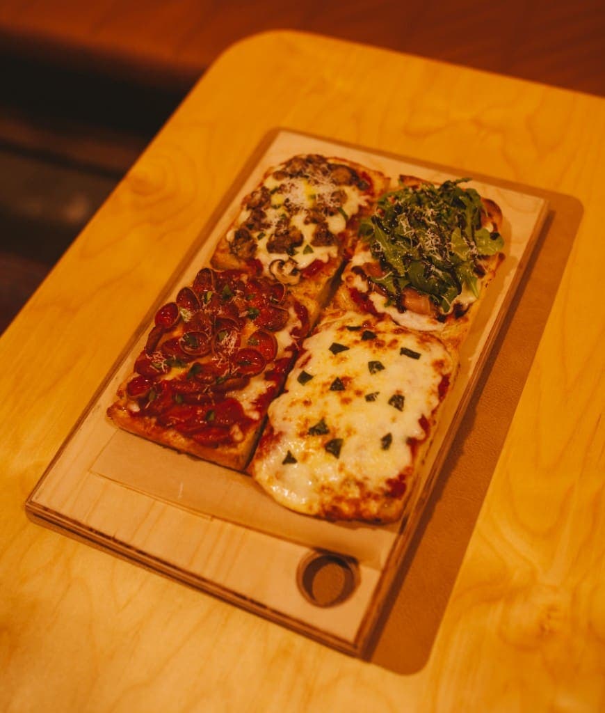 Four thick-crust pizza slices on a wooden board at The Analogue Room in Solvang