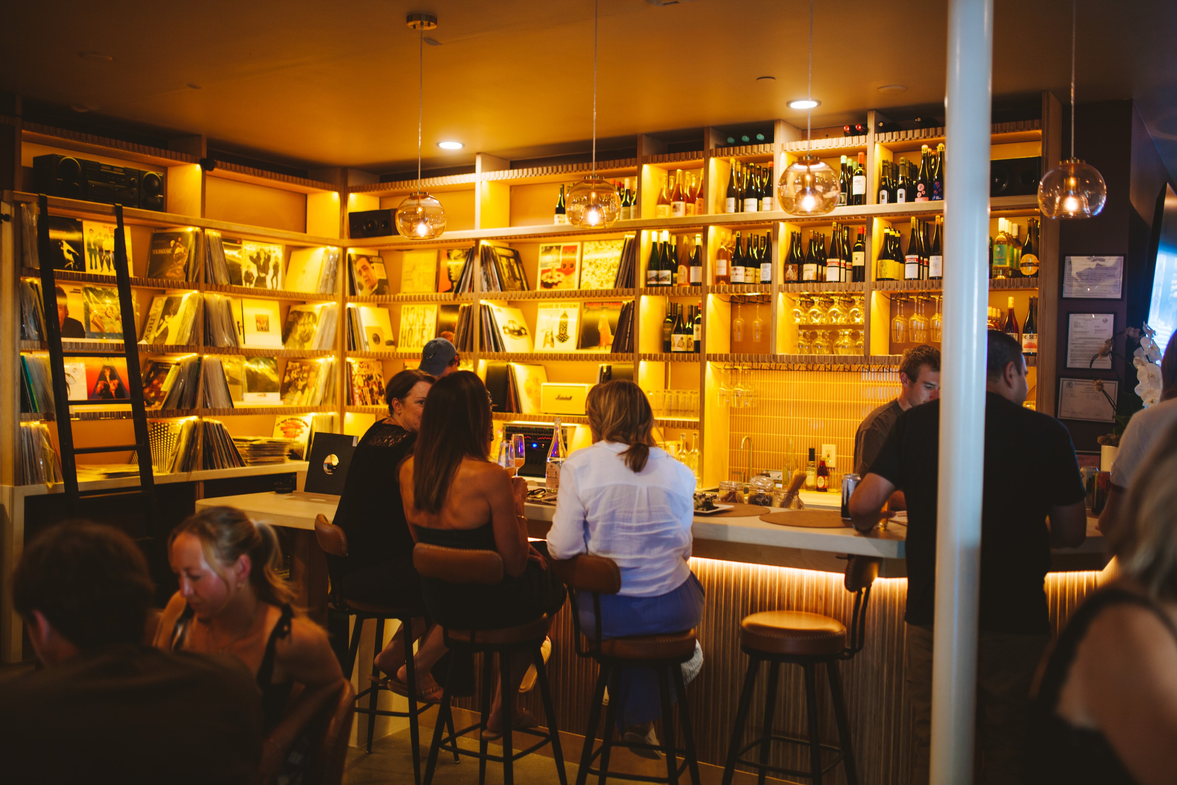 Guests at the bar with vinyl shelves and wine bottles at Analogue Room in Solvang